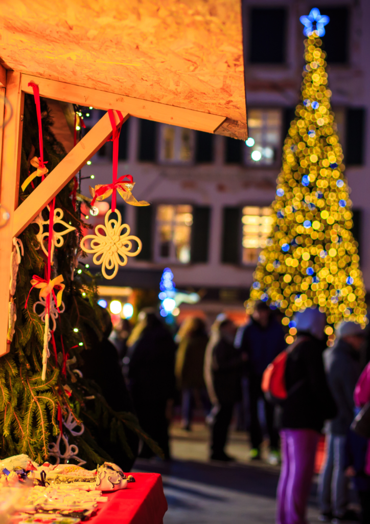 close up of ornaments and a christmas tree, people in the background