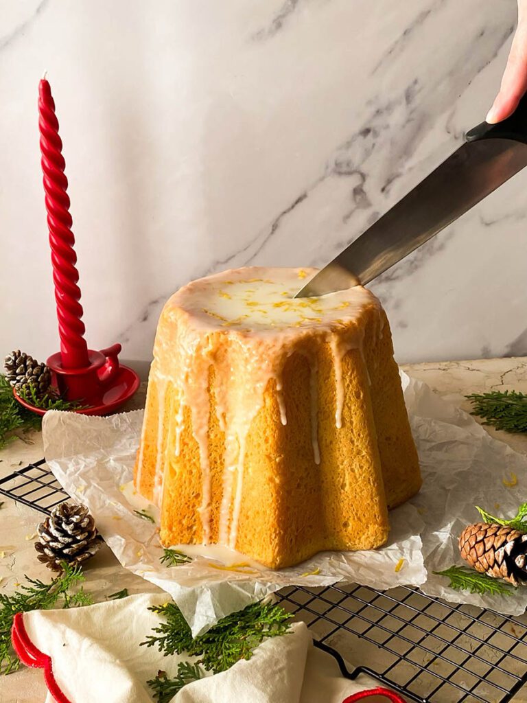 limoncello pandoro on a cooling rack with greenery, pinecones and a red candle