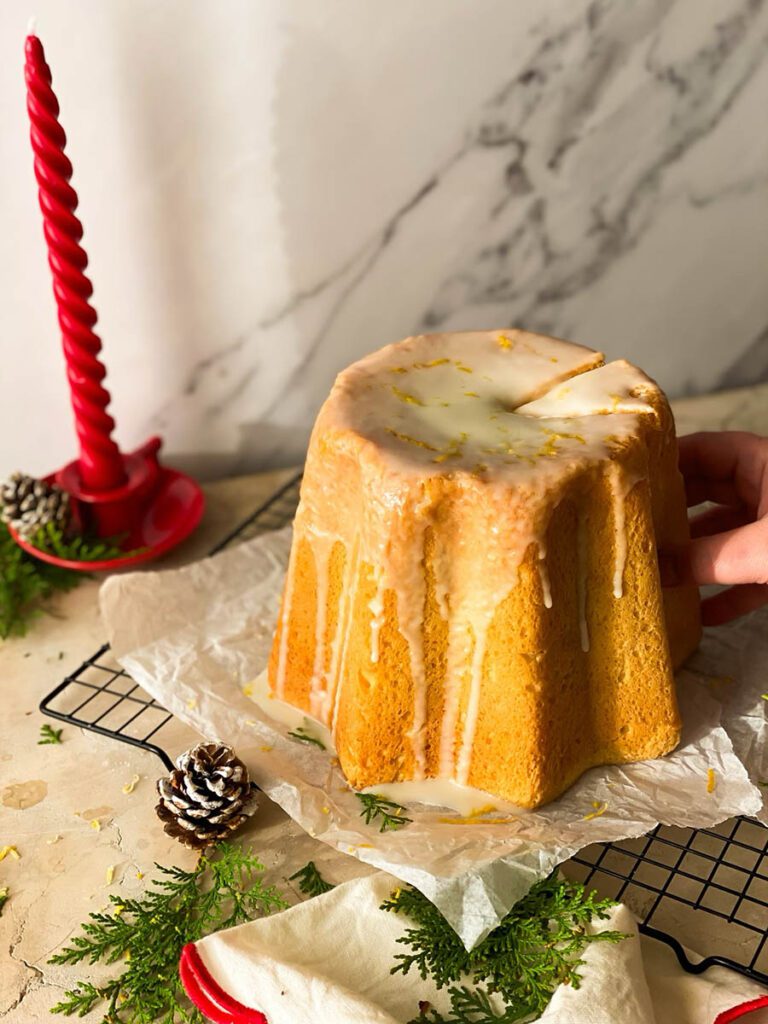 limoncello pandoro on a cooling rack with greenery, pinecones and a red candle