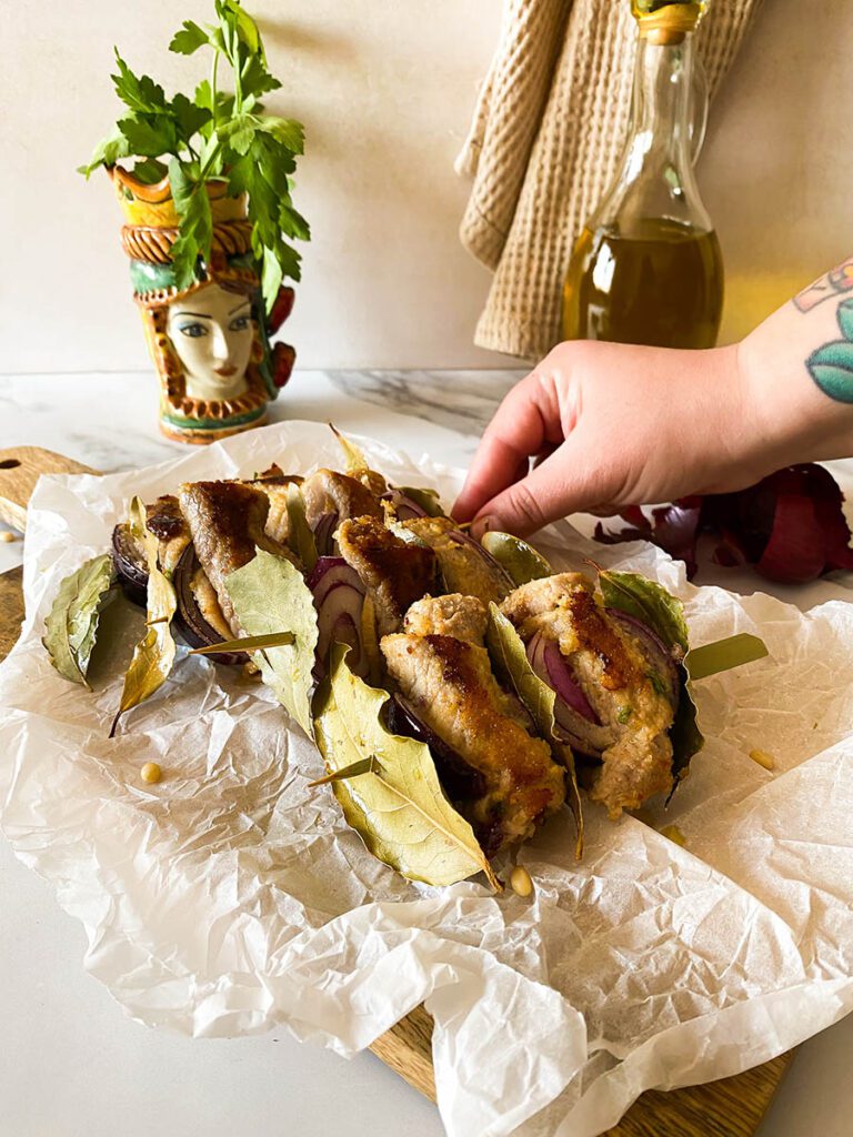 involtini alla siciliana over some bakoing paper with olive oil and red onion on the background