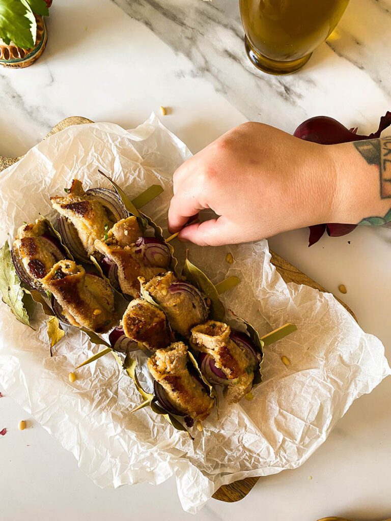 involtini alla siciliana over some bakoing paper with olive oil and red onion on the background
