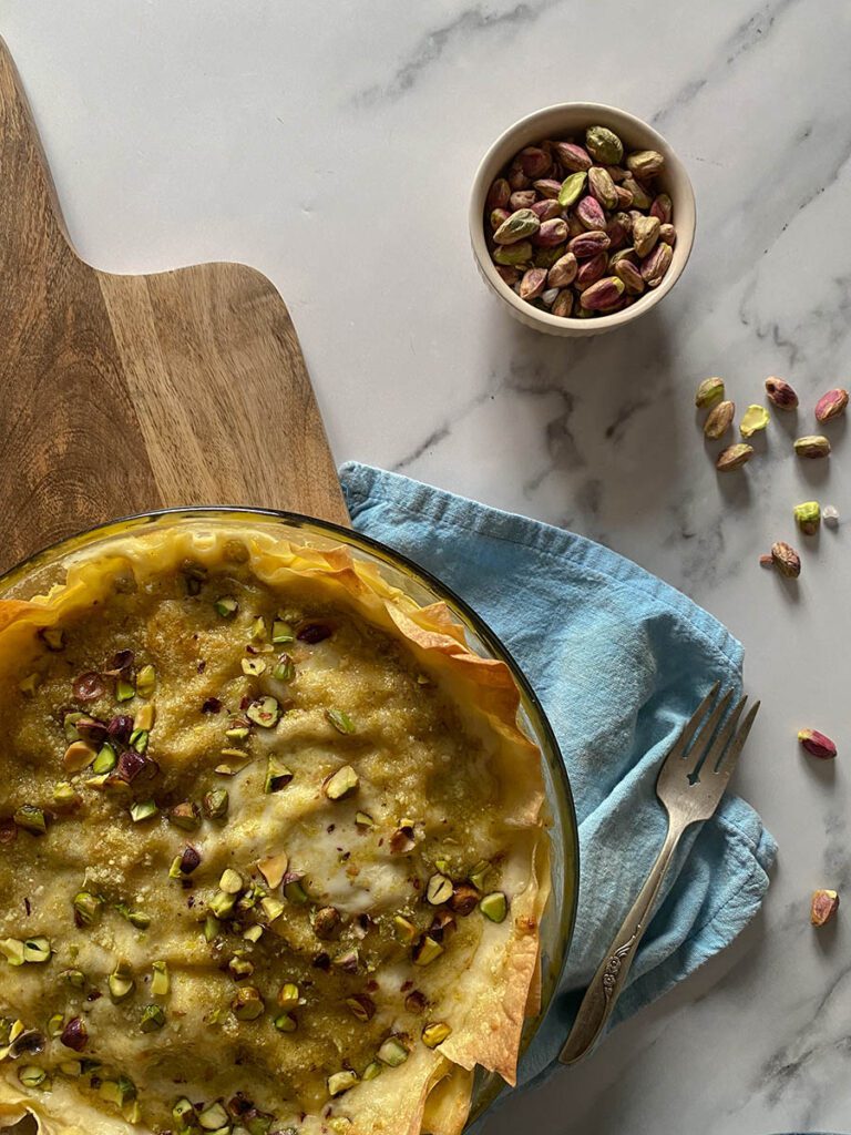 pistachio lasagna over a wooden board and light blue napkin