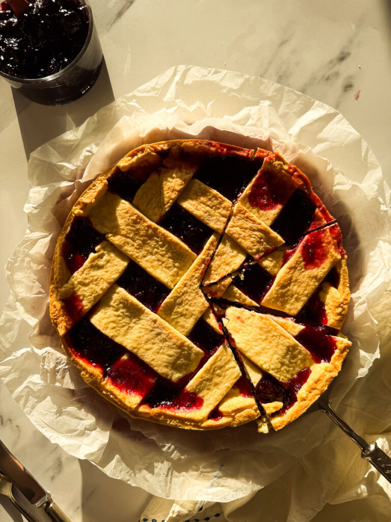 from top, crostata on a marble background, jam on the side and cutlery