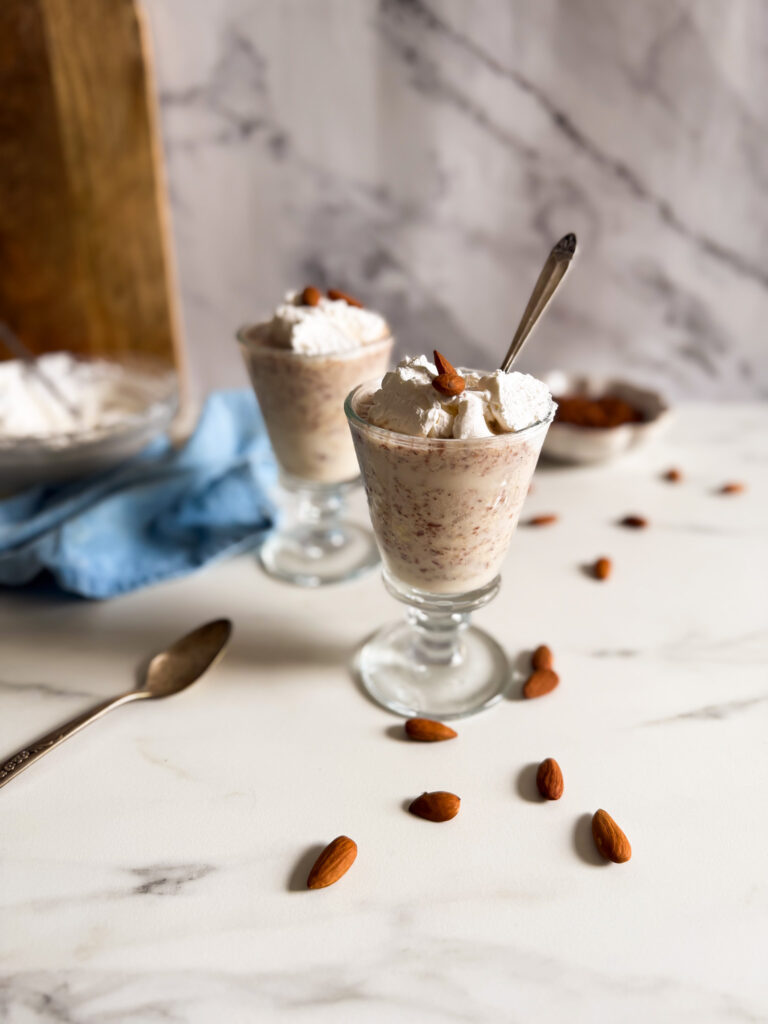from 45 granita di mandorle in two tall glasses, spoon, almonds and cream in the background