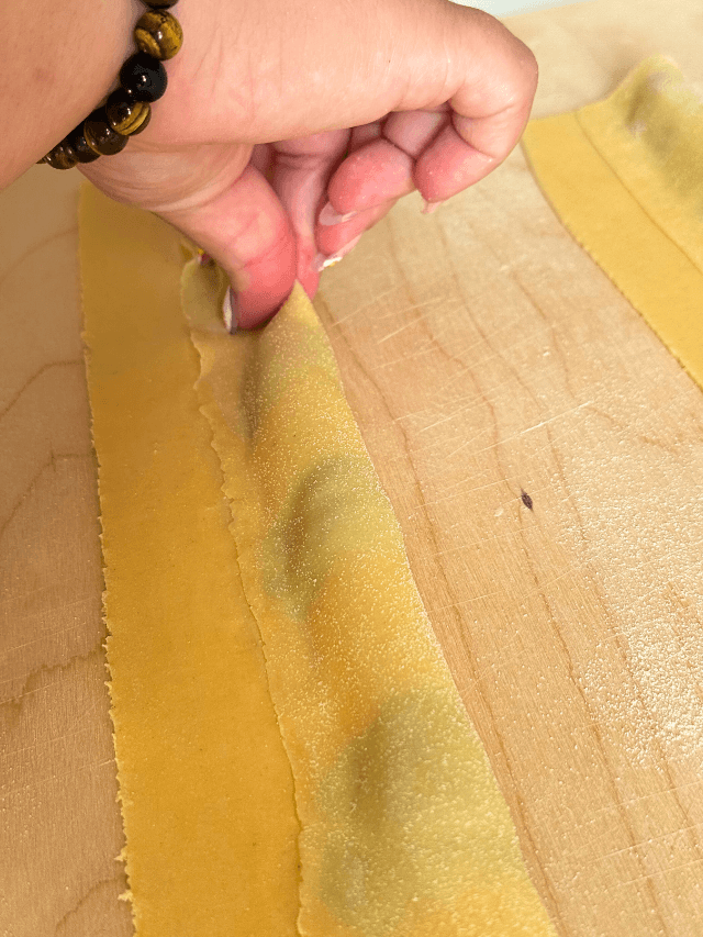 hand pinching the ricotta agnolotti, on a wooden board, on marble background